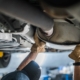 Mechaniker inspiziert den Katalysator des Fahrzeugs bei der planmäßigen Überprüfung des Abgassystems. Thema Autowartung.