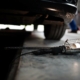 Werkstattleuchte liegt auf dem Boden, Auto steht auf einer Grube in der Werkstatt