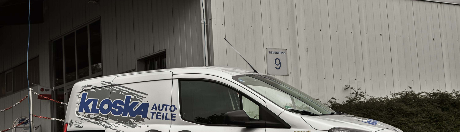 Ein Auto von Kloska steht vor der Halle von Kloska Autoteile in Kall