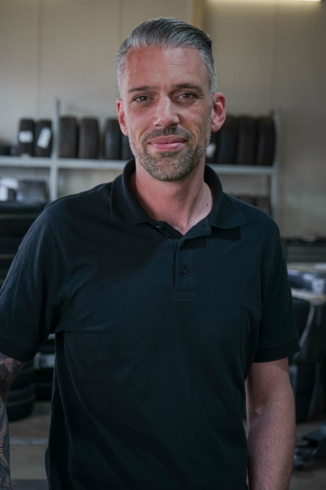 Michael Görres steht lächelnd in der KFZ-Werkstatt.